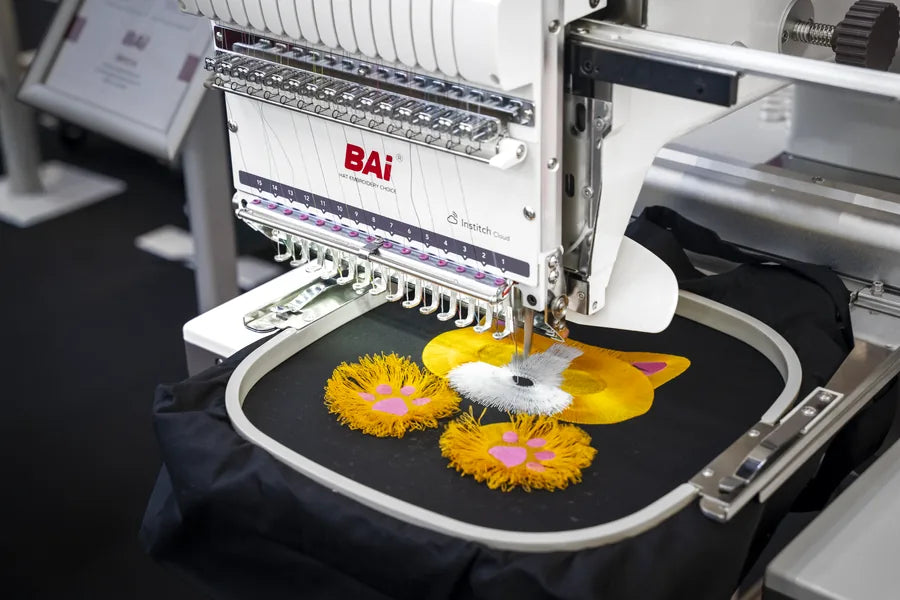 A BAI machine stitching raised 3D puff lettering on a black garment